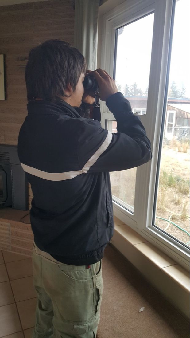Side view of man holding up and looking through binoculars.
