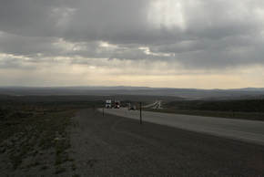 Photo of Interstate 80, with dramatic clouds overhead and several semi-trucks approaching the viewer. Angle of the photo emphasizes how big the road is.