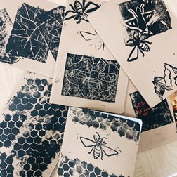 Photo of the covers of students' journals with prints of bees, honeycomb, mountains, mushroom, and trees.