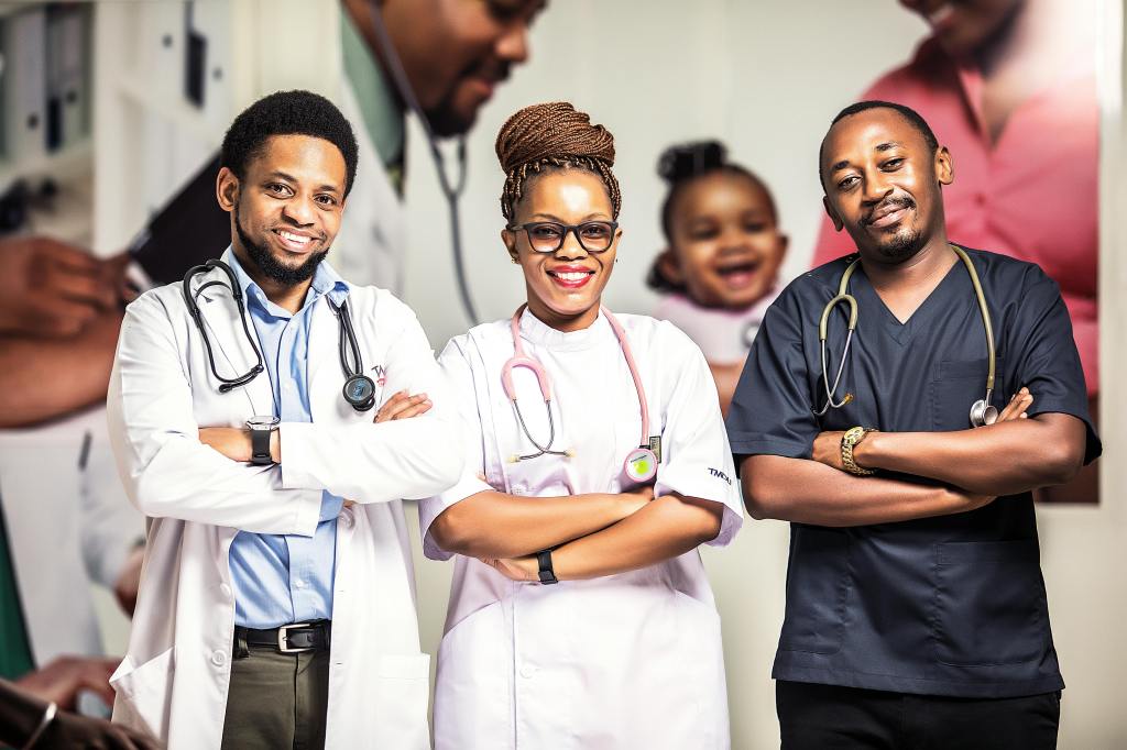 Three medical professionals stand in a row, all with their arms crossed and smiles on their faces. Each has a stethoscope around their neck. 